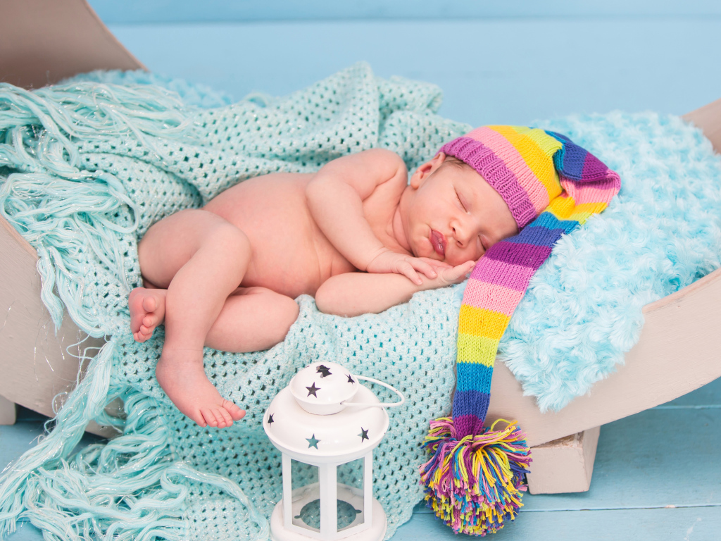 Спящий грудной ребенок в большой вязаной шапке