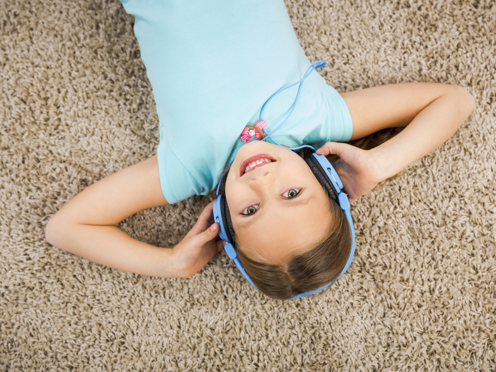 Улыбающаяся девочка в больших голубых наушниках