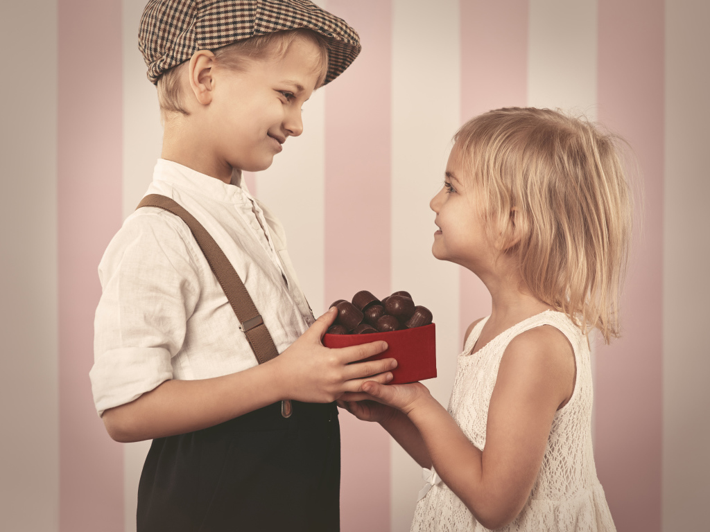 Мальчик дарит девочке коробку шоколадных конфет