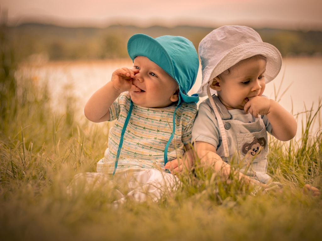 Два милых малыша в зеленой траве летом 