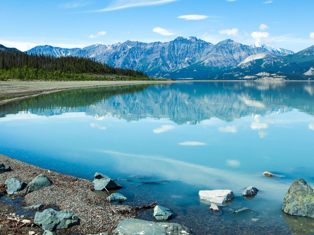 Горы отражаются в голубой воде озера Клуэйн, Национальный парк на территории Юкон, Канада.