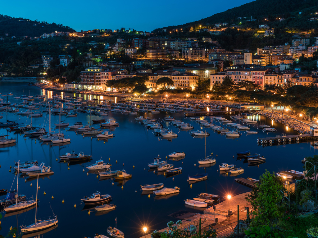 Панорама ночного города и лодки на причале у побережья, Лигурия. Италия