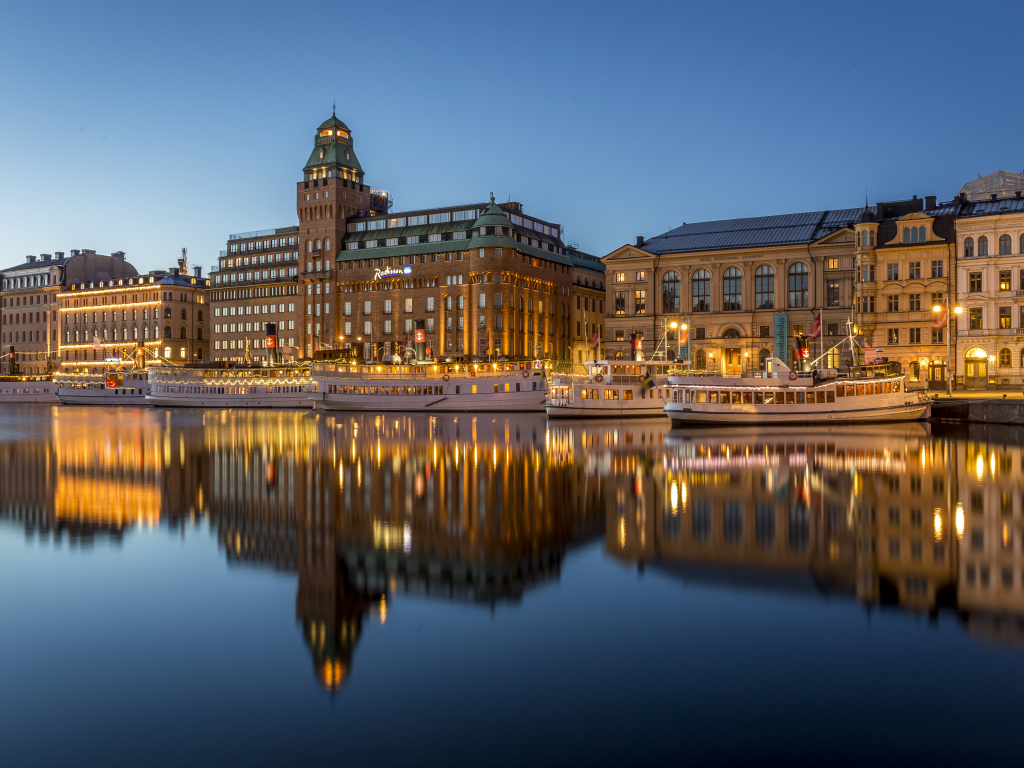 Красивые дома отражаются в воде у причала вечером, Стокгольм. Швеция