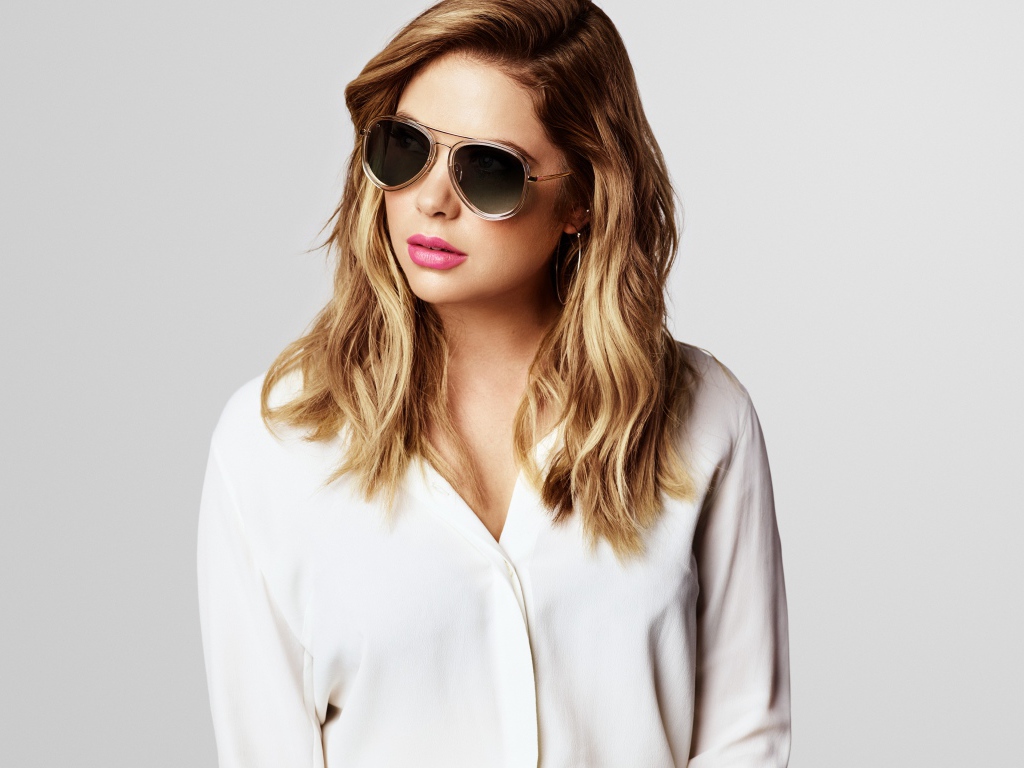 Актриса Эшли Бенсон в черных очках на сером фоне