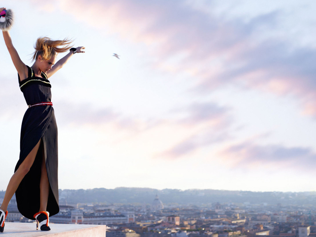 Актриса Кара Делевинь в черном платье на фоне неба 