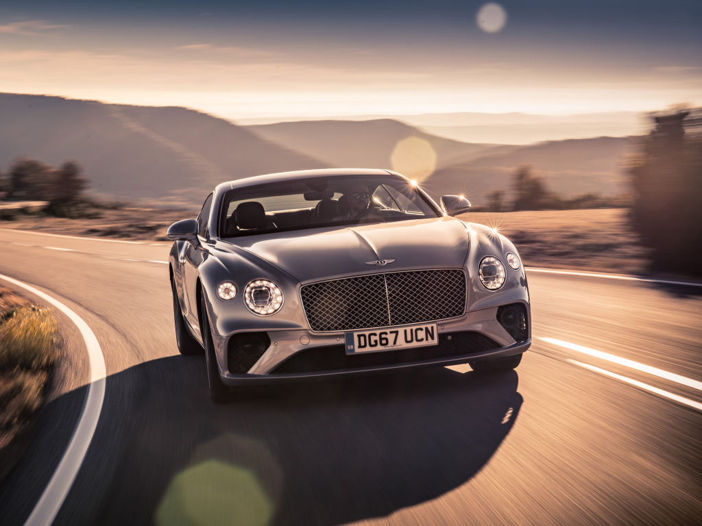 Серебристый автомобиль Bentley Continental GT 2018 года на трассе