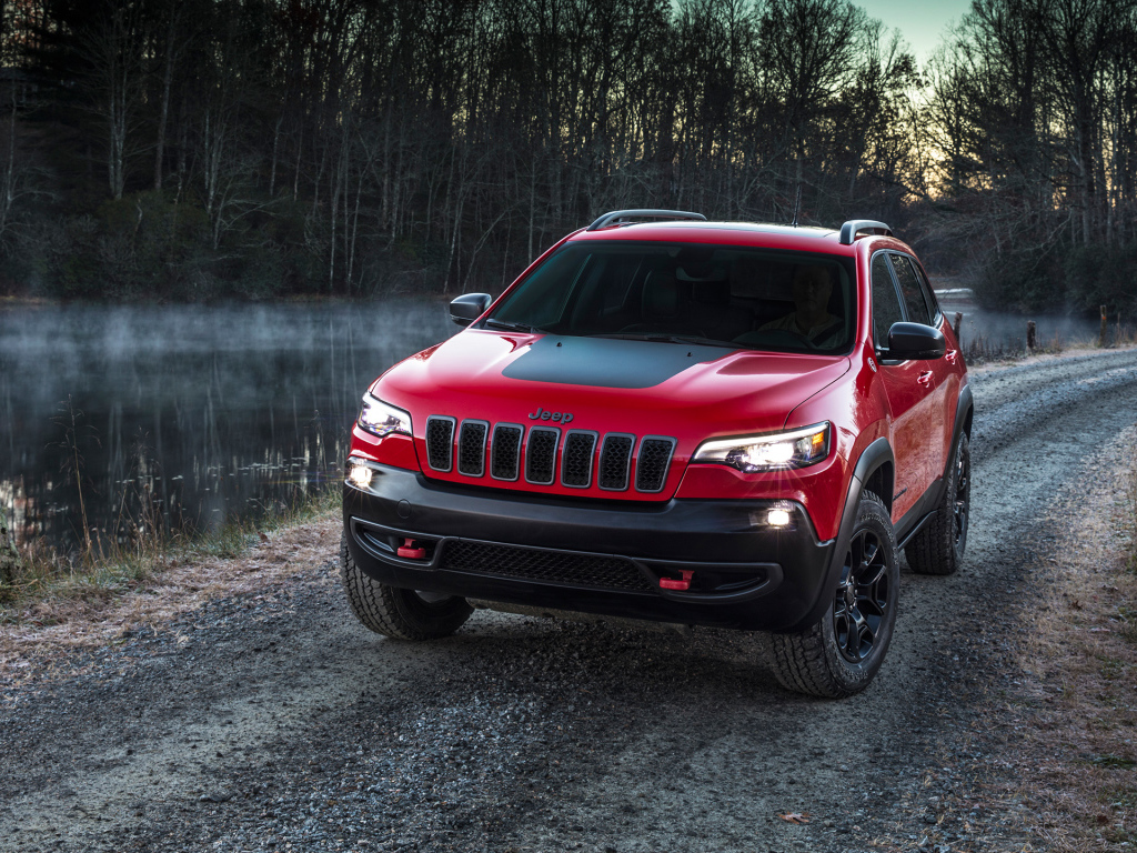 Красный автомобиль Jeep Cherokee Trailhawk, 2019 на дороге у реки