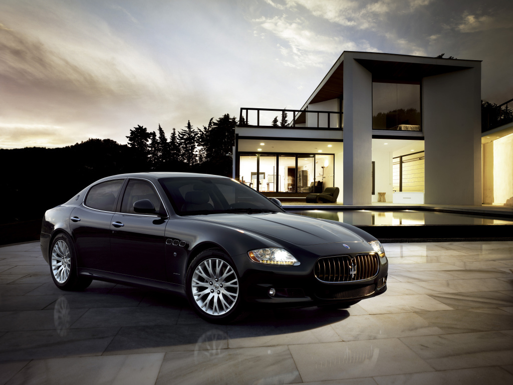 Черный автомобиль  Maserati Quattroporte у большого дома