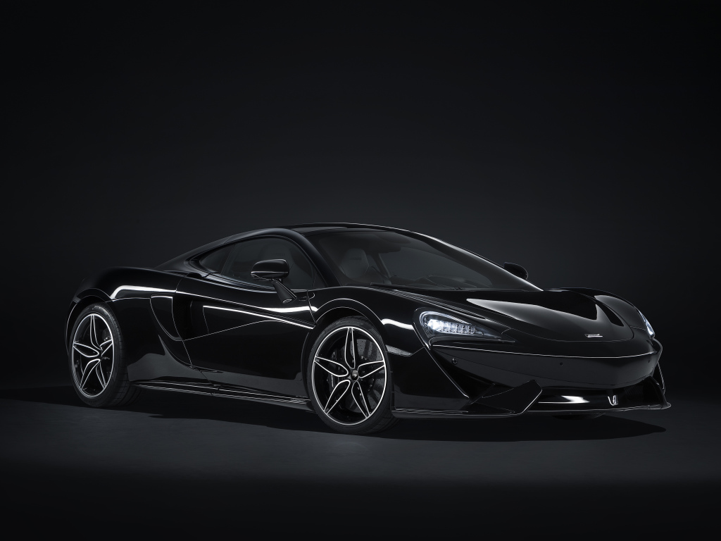 Черный спортивный автомобиль McLaren 570GT на сером фоне