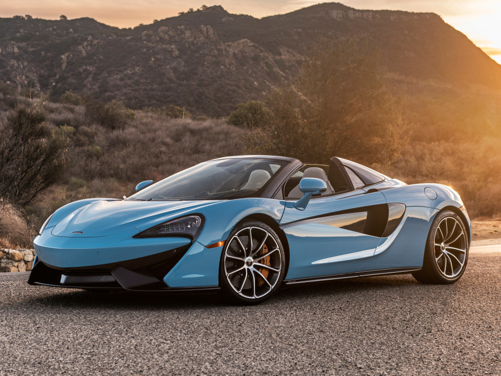Голубой спортивный автомобиль  McLaren 570S Spider, 2018 на фоне солнца