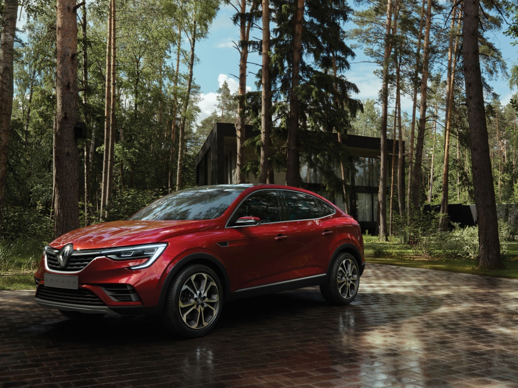 Красный стильный внедорожник Renault Arkana, 2018 года в лесу