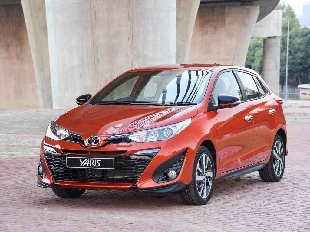 Красный автомобиль Toyota Yaris под мостом 