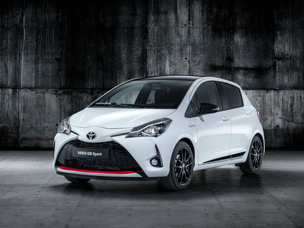 Белый автомобиль Toyota Yaris на сером фоне 
