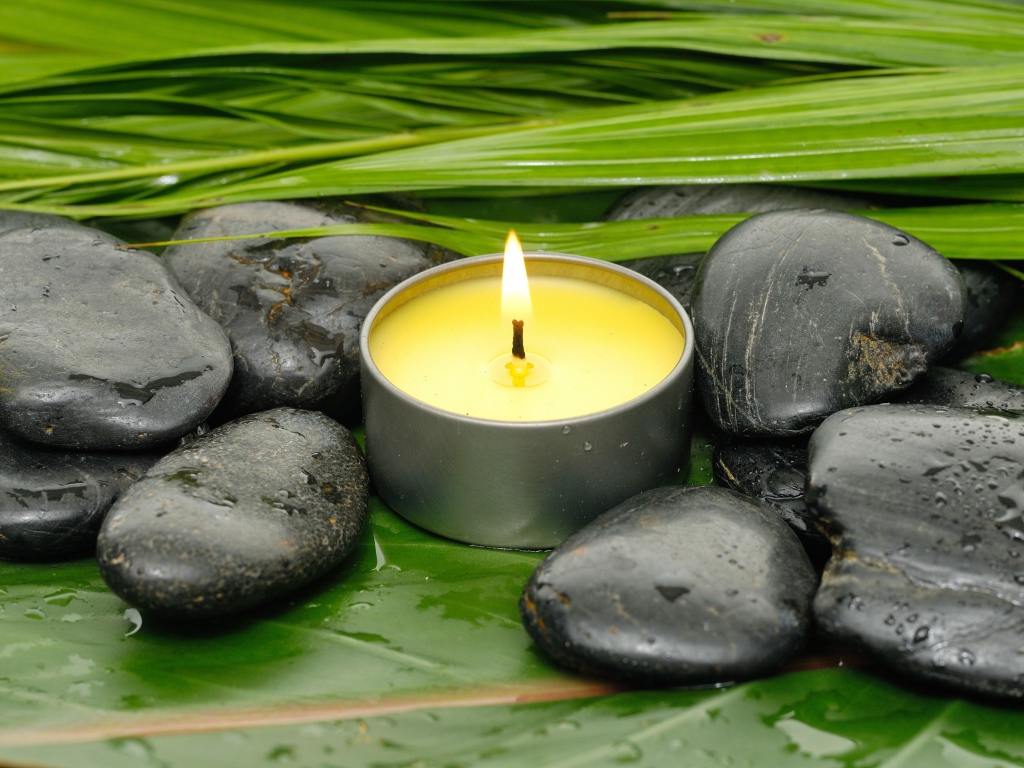 Зажженная свеча и черные камни для SPA