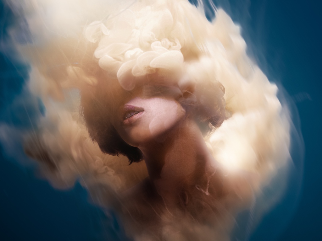 Лицо девушки в дыму на голубом фоне, иллюзия