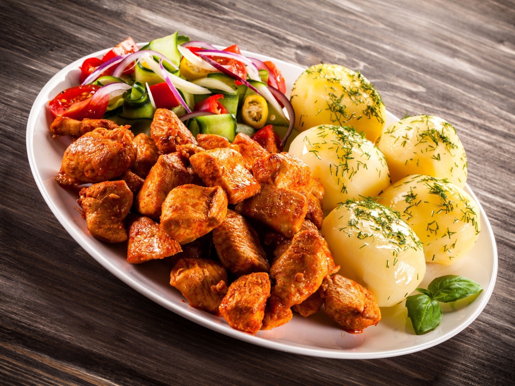 Вареный картофель с мясом и салатом на тарелке