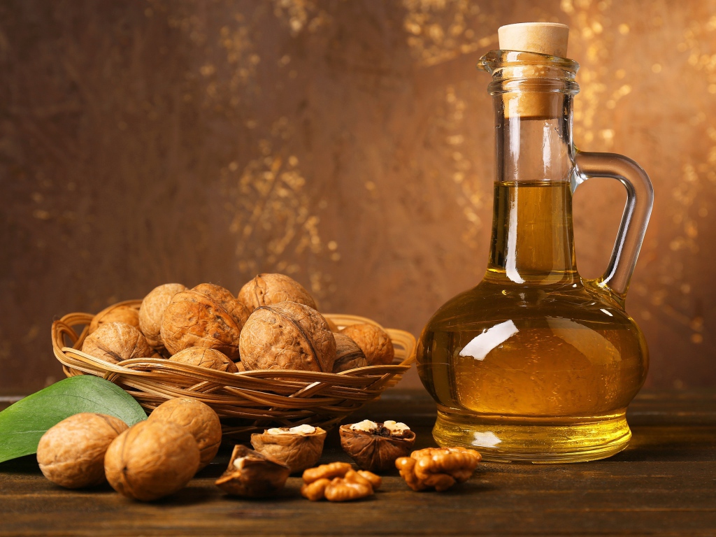 Масло в стеклянной бутылке на столе с грецкими орехами 