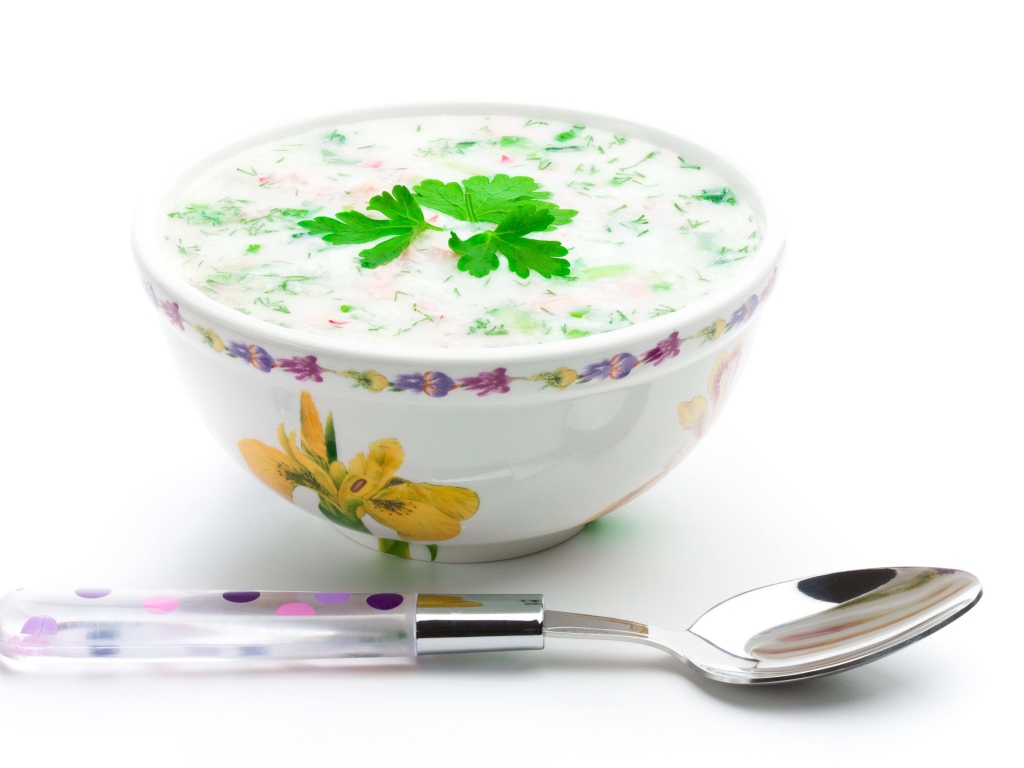 Аппетитная вкусная окрошка в тарелке на белом фоне с ложкой 