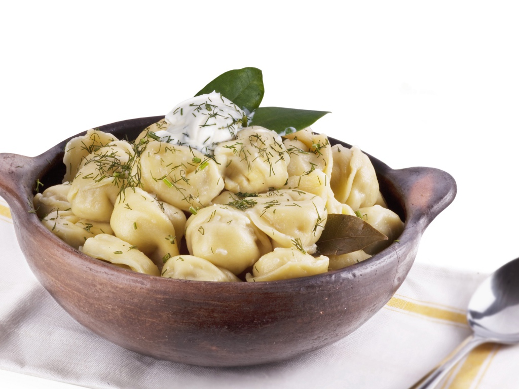 Пельмени в миске на белом фоне с ложкой 