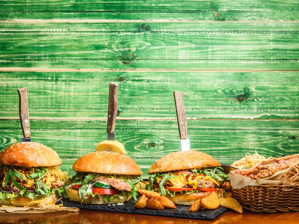 Гамбургеры с ножами на деревянном фоне