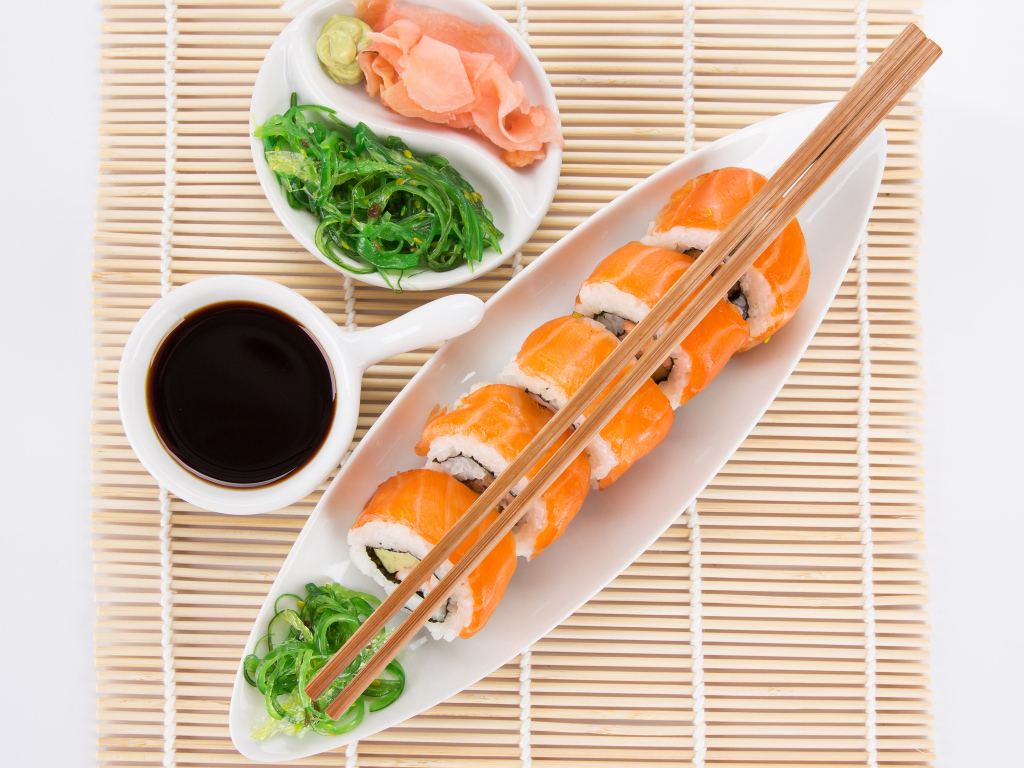Японские суши на столе с соевым соусом и имбирем с салатом