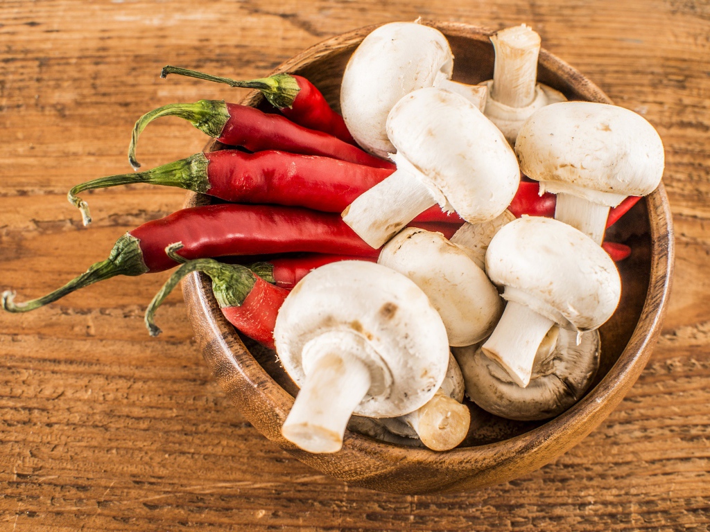 Грибы шампиньоны в деревянной миске с красным перцем