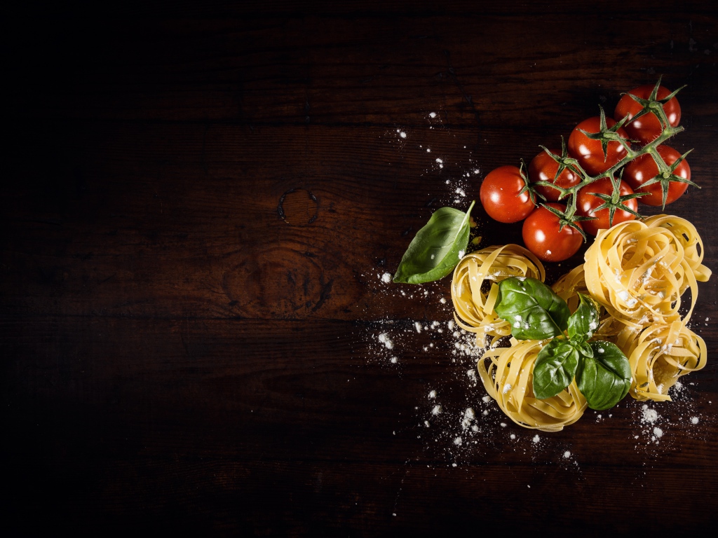 Паста с помидорами и листьями базилика на столе