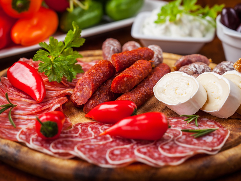 Колбаса с кусками сыра и мяса на столе с перцем