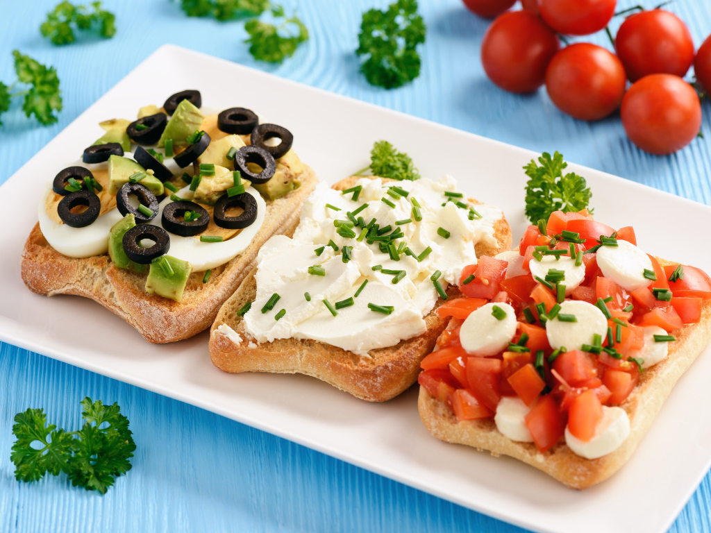 Три аппетитных бутерброда на столе с помидорами и петрушкой