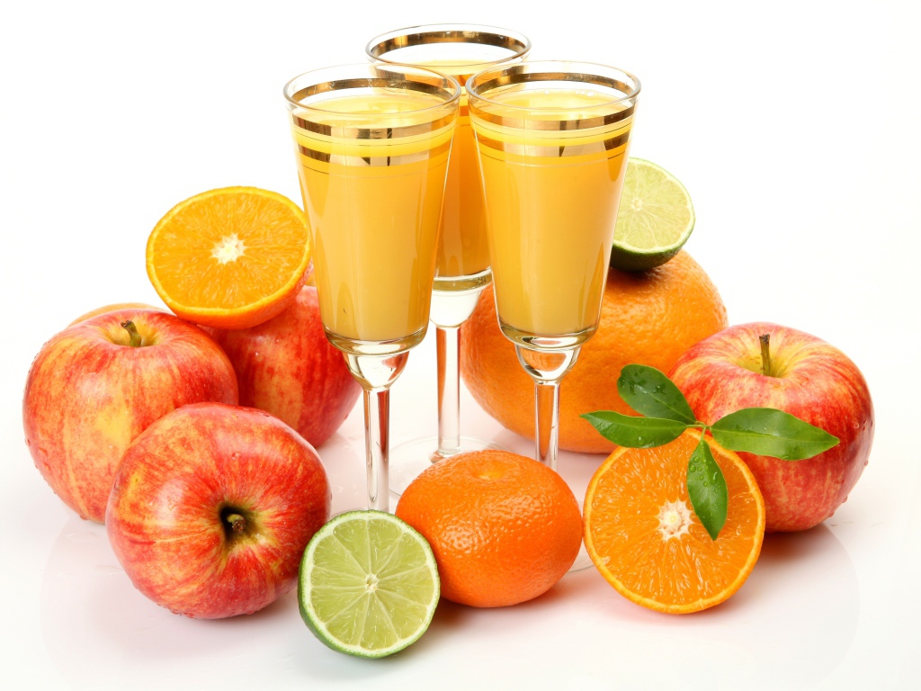 Three glasses of juice on the table with apples and oranges on a white background