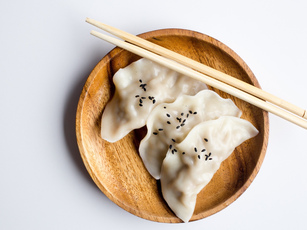 Три вареника на деревянной тарелке с палочками