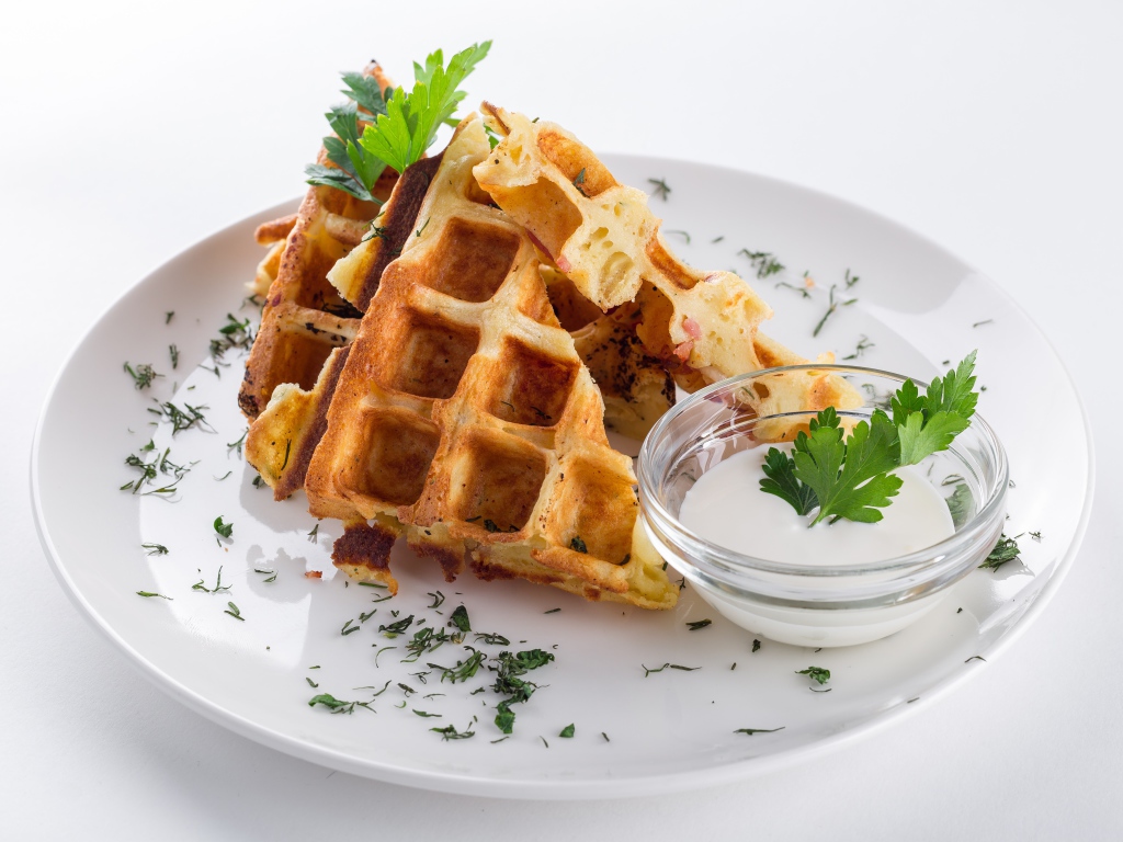 Несладкие вафли на белой тарелке с зеленью и соусом