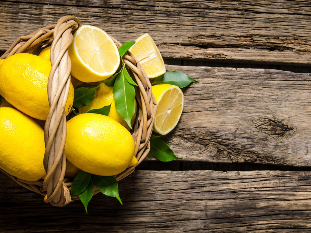 Красивые желтые лимоны в корзине на деревянном столе