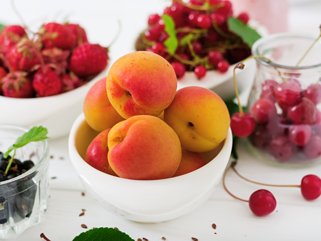 Свежие абрикосы на столе с ягодами крупным планом