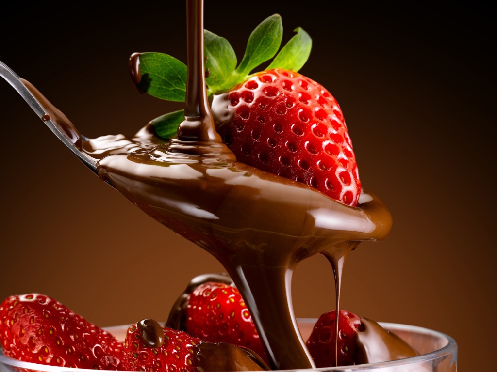 Свежая красная клубника на ложке с шоколадной пастой