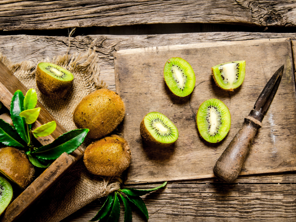 Нарезанное киви на разделочной доске с ножом