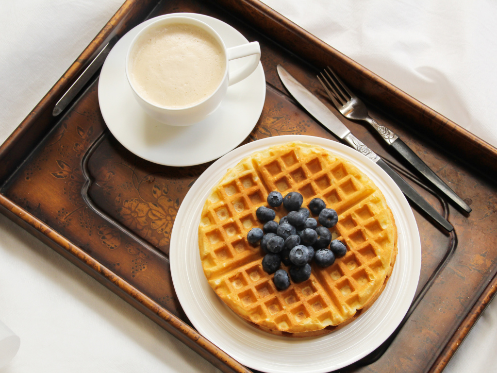 Чашка кофе и сладкие вафли с черникой на завтрак