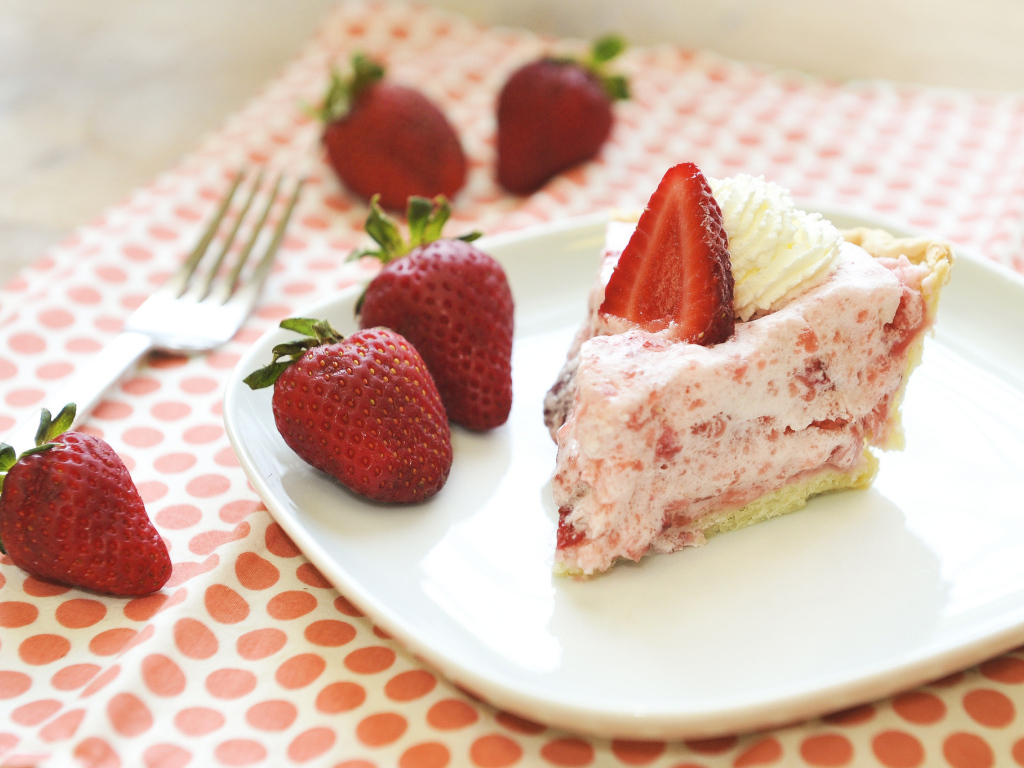 A piece of cake on a plate with fresh strawberries