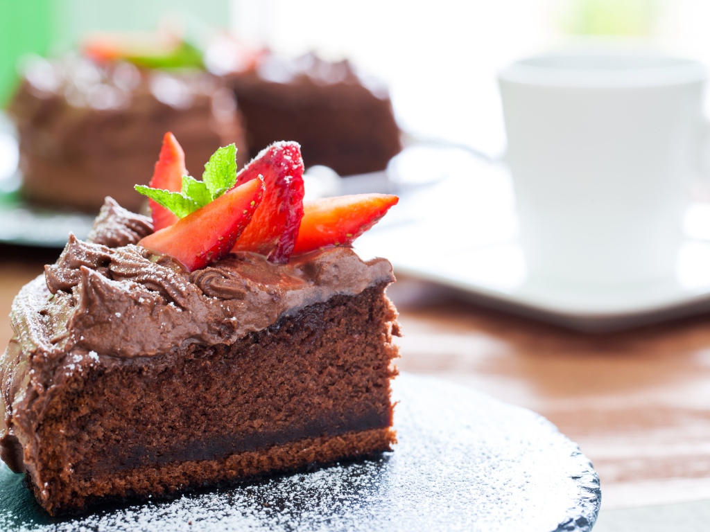 Кусок пирога с шоколадным кремом и кусочками спелой клубники 