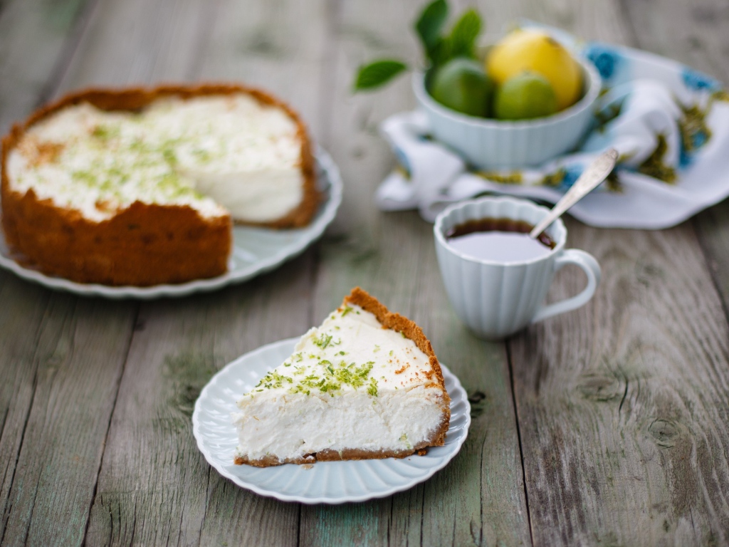 Кусок чизкейка на столе с чашкой чая