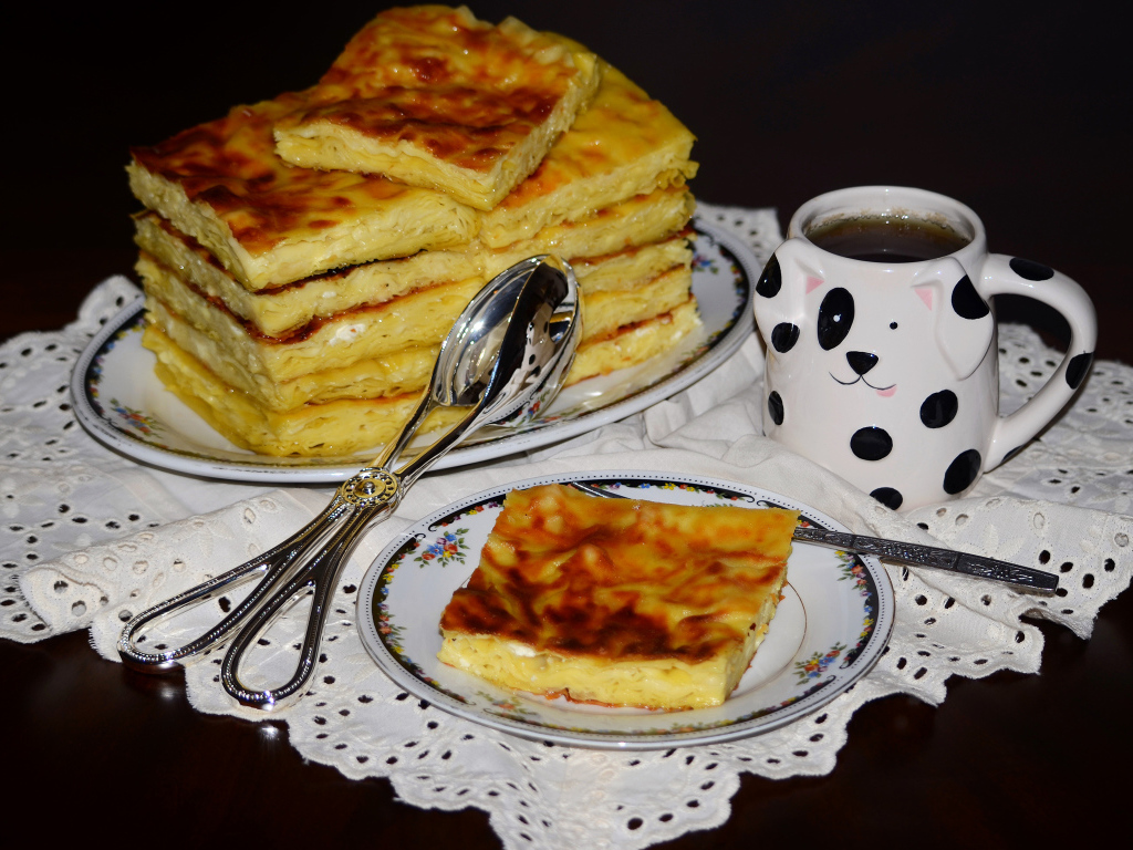 Аппетитный сладкий пирог с чашкой чая на столе