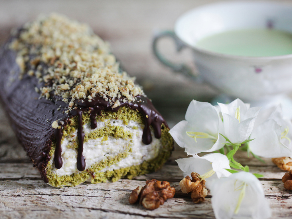 Аппетитный сладкий рулет с шоколадом на столе с белыми цветами колокольчика