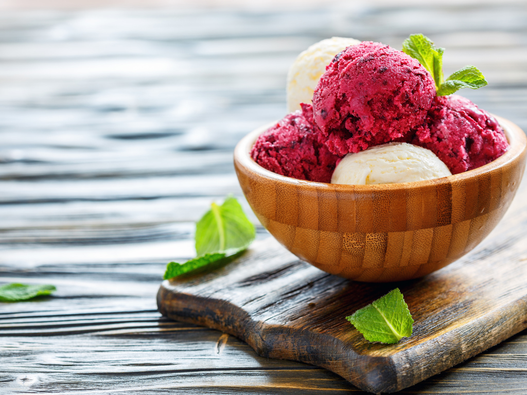 Шарики фруктового и ванильного мороженого в деревянной миске на столе