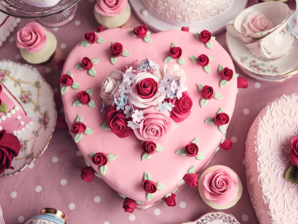 Красивый праздничный розовый торт в форме сердца украшен цветами