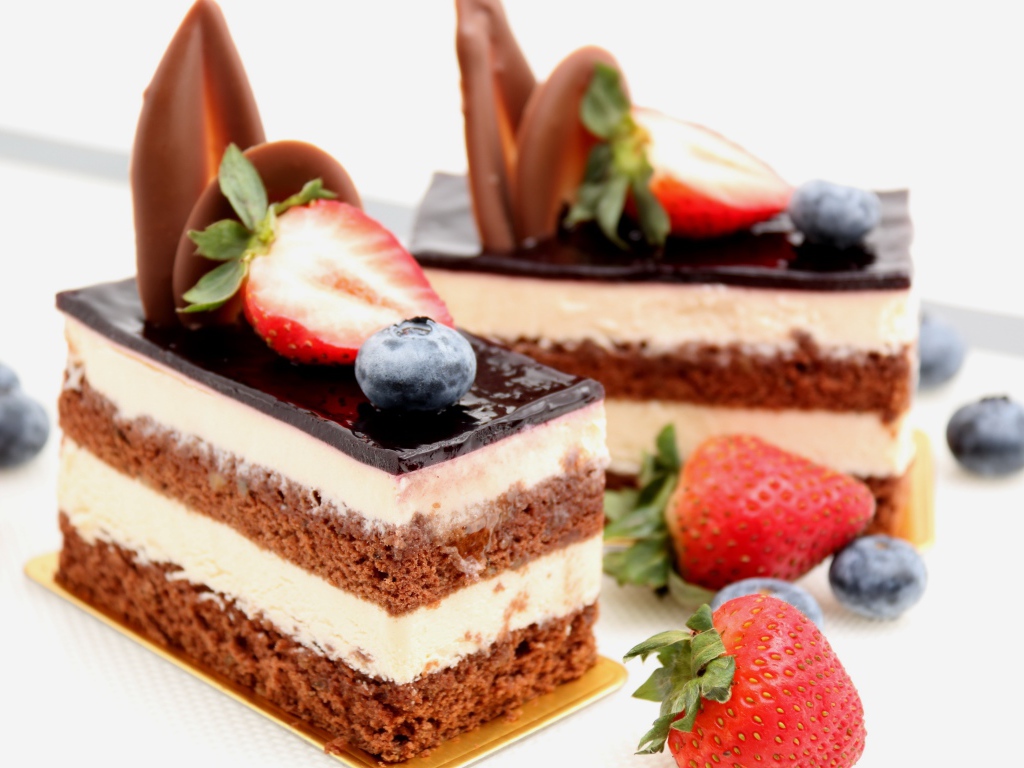 Пирожные с шоколадом, кремом и ягодами клубники и черники