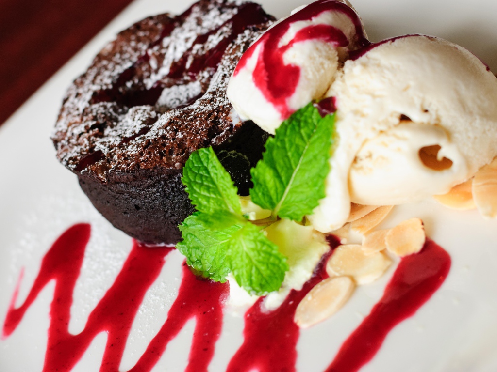 Шоколадное пирожное с мороженым и джемом на тарелке
