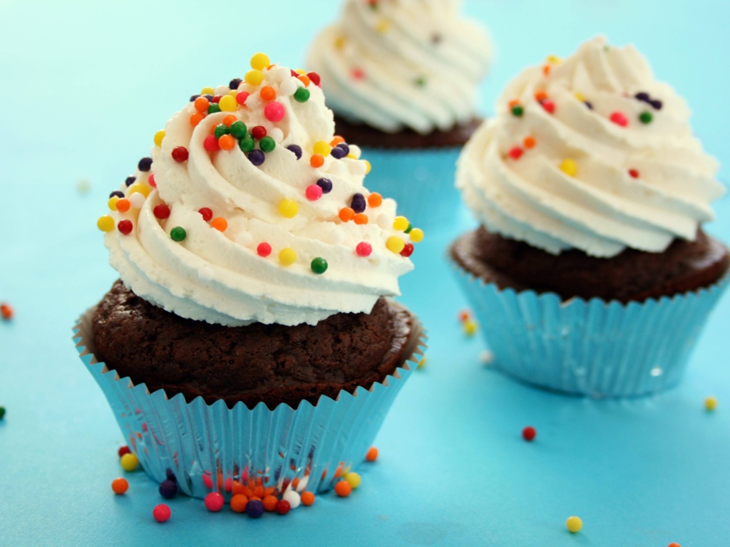 Шоколадные кексы со сливками и цветными брызгами на голубом фоне