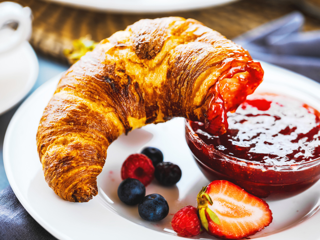 Круассан с джемом и ягодами на тарелке