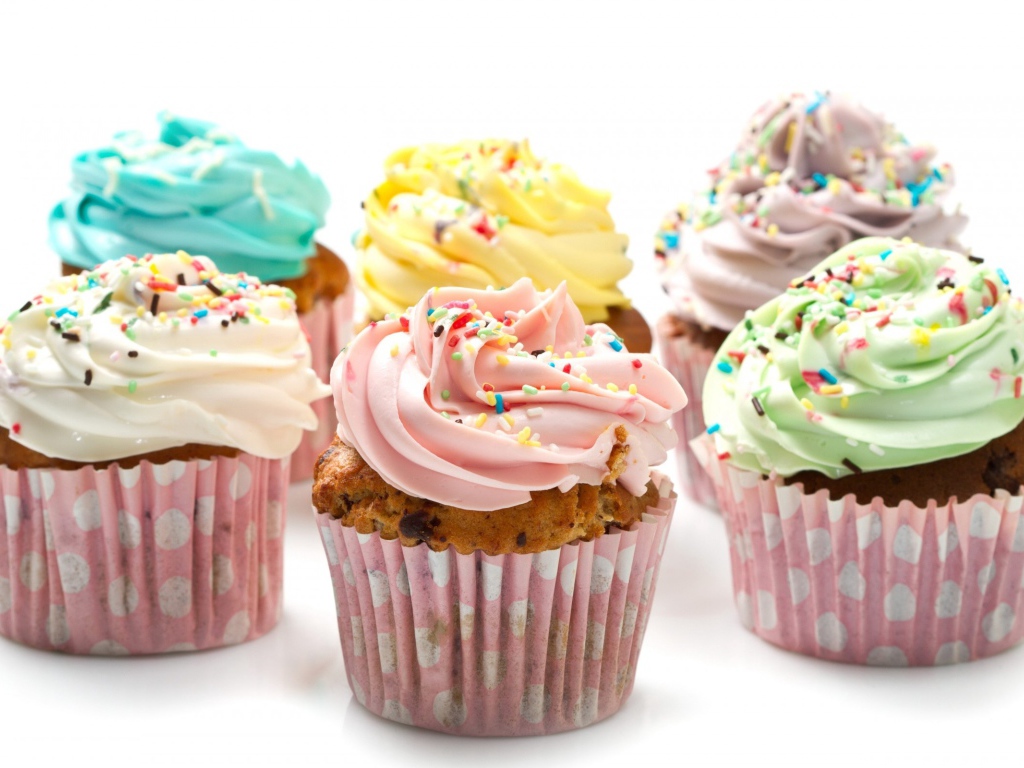 Кексы с разноцветным кремом на белом фоне