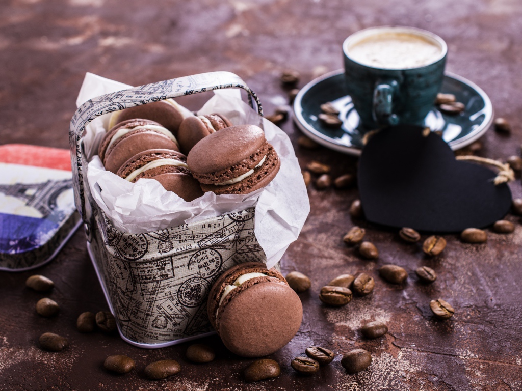 Десерт макарон на столе с кофейными зернами и чашкой кофе